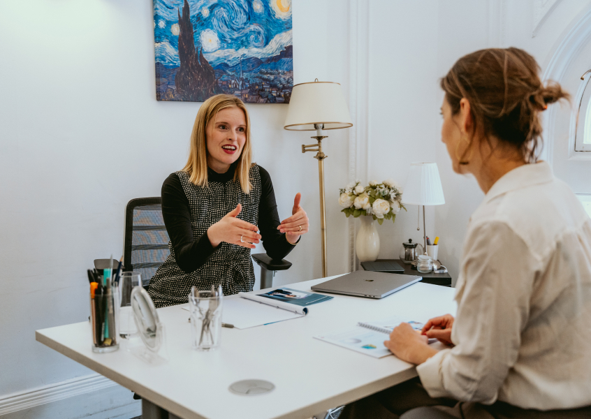 Two professionals engaged in a calm, guided conversation during a conflict coaching session